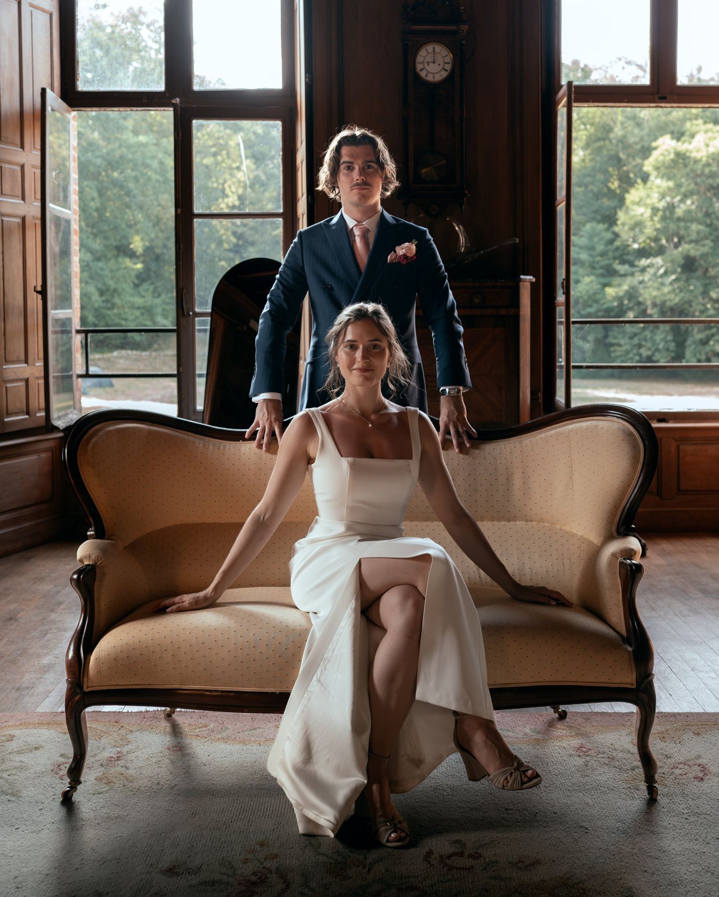Portrait des mariés dans le salon d'un château, la mariée assise sur un canapé ancien