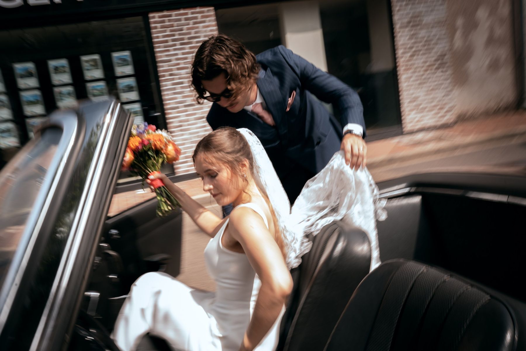 La mariée monte dans une voiture de collection, photo de mariage en mouvement